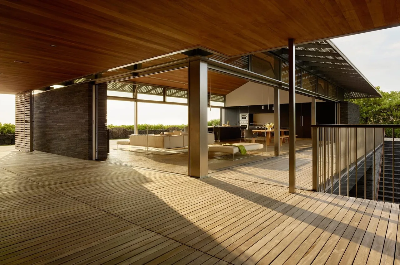 Open living space with sliding glass walls, wood decking, and ceiling in a modern residence.