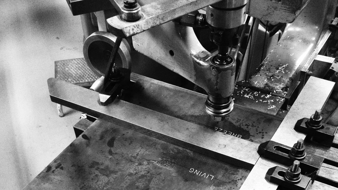 Metal engraving machine spelling 'LIVING BREEZE' on a metal plate for the Napa Residence project.