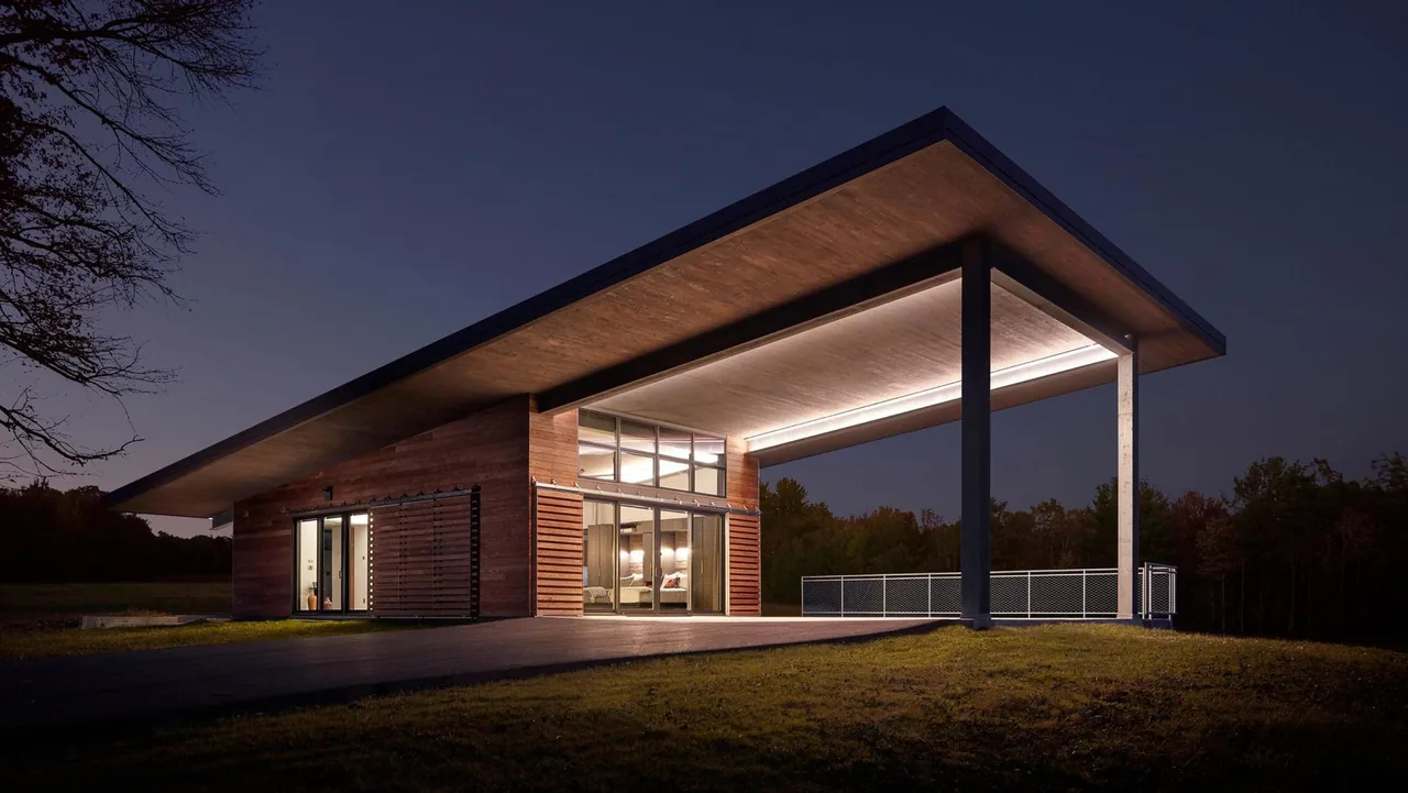Flying Dollar Residence features a deep roof overhang with wood siding and floor-to-ceiling windows.