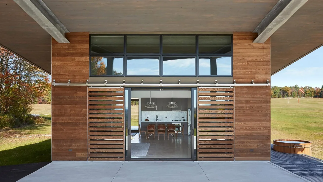 Modern home's rear exterior with wood siding and sliding wood slat screens opening to the kitchen and dining area.