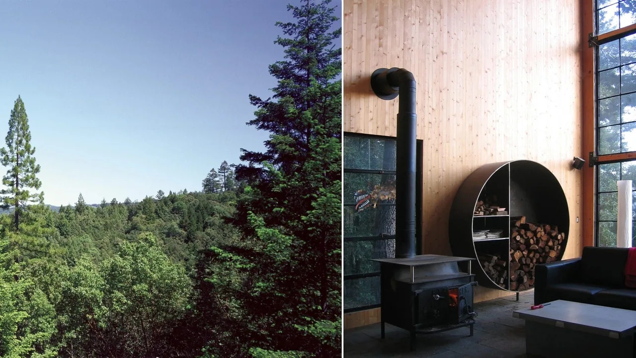 Living area of Lundberg/Breuer Cabin features a wood stove and circular firewood storage with large grid windows.