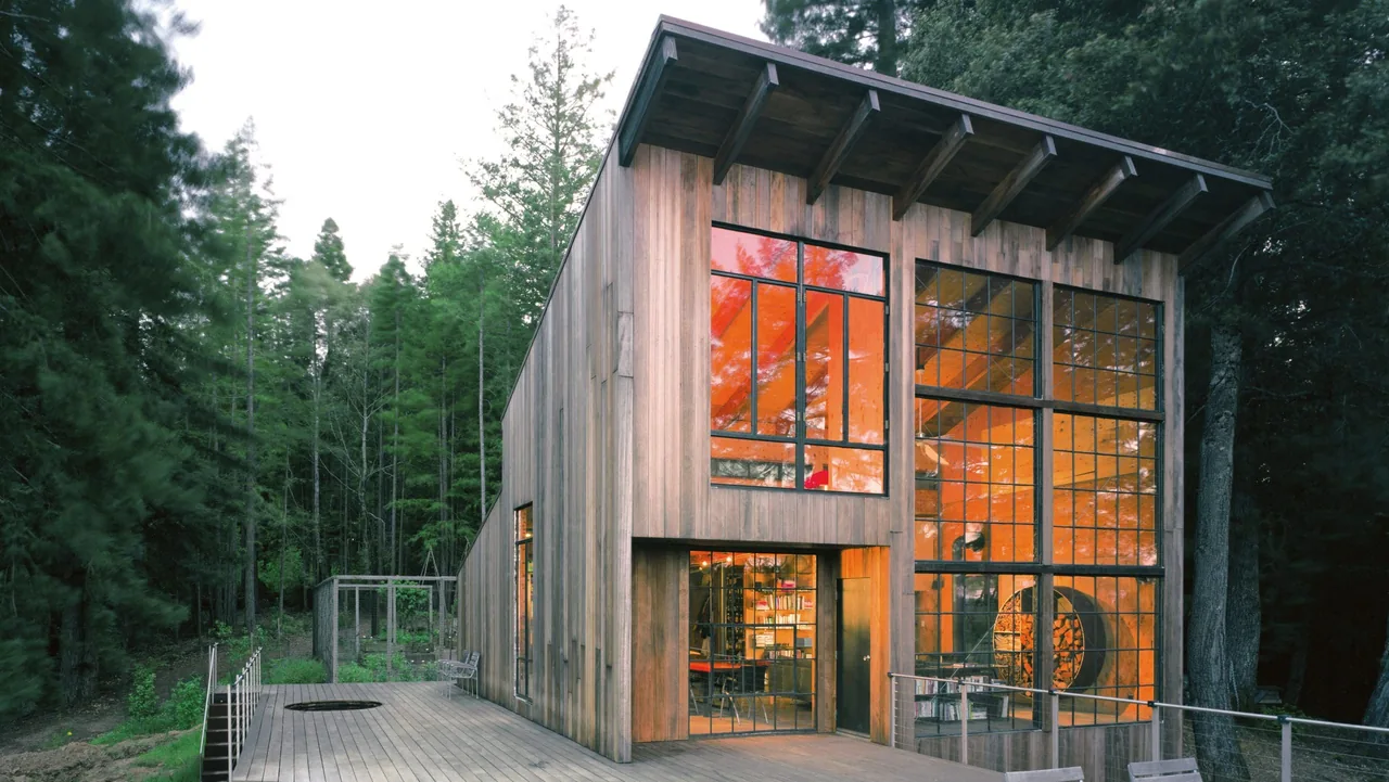 Lundberg/Breuer Cabin features vertical wood siding and large metal grid windows showcasing timber construction.