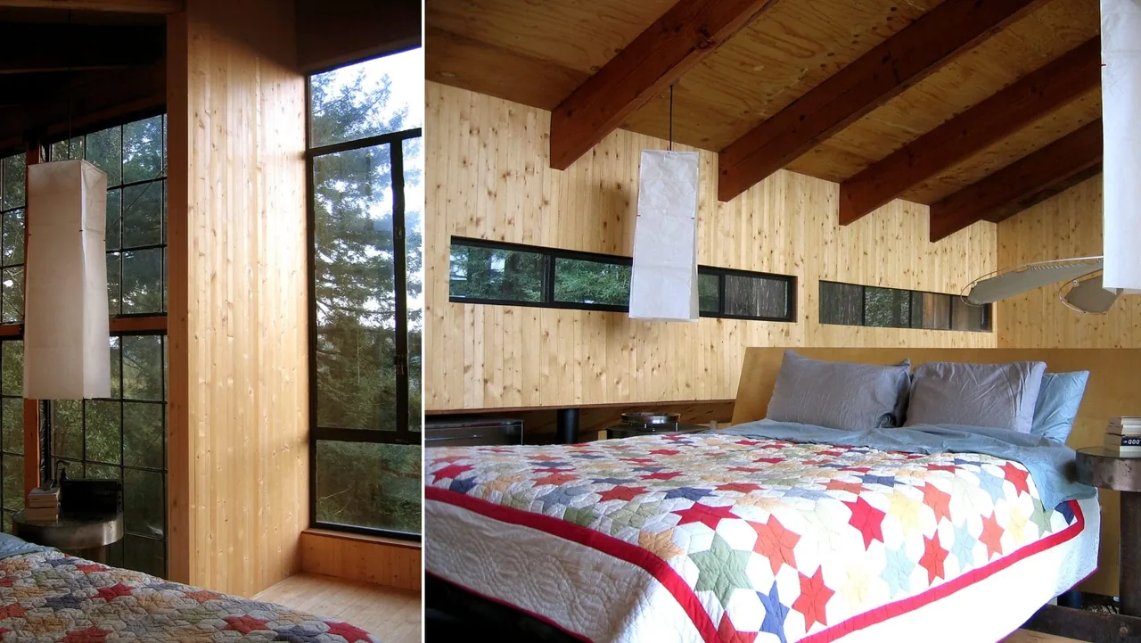 The Lundberg/Breuer Cabin bedroom features wood paneling and horizontal slit windows under exposed beam ceilings.