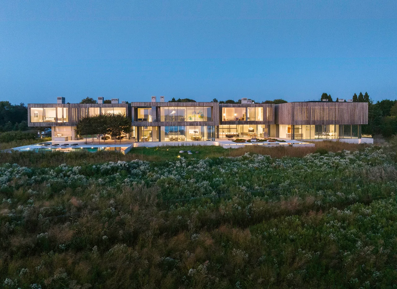 Modern two-story house with extensive glazing and wood siding photographed at dusk.