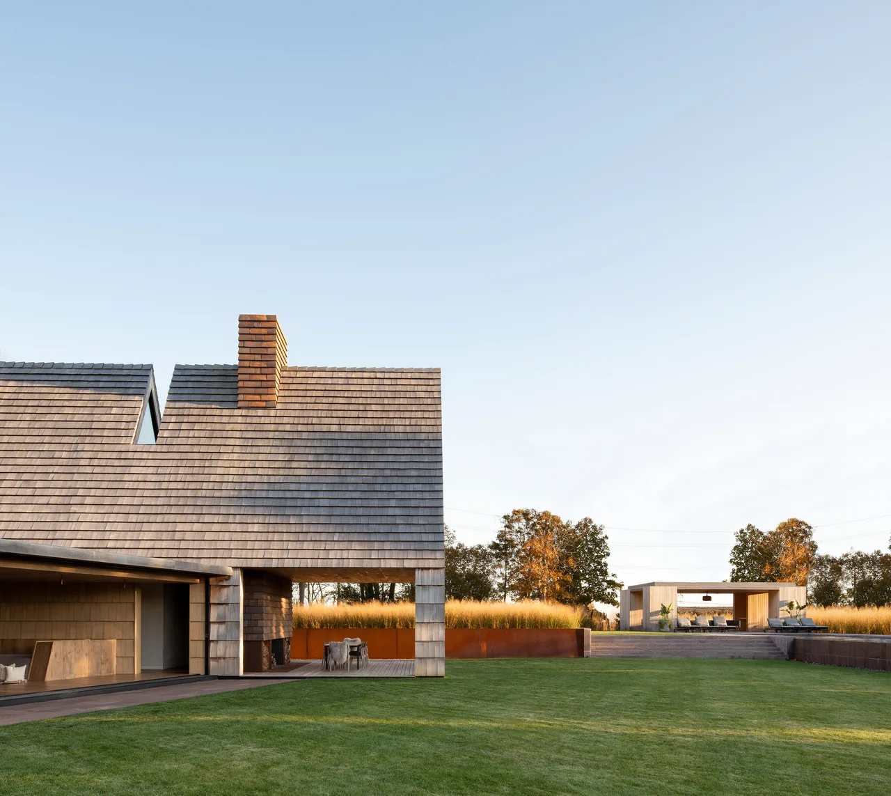 Stony Hill house features steep gable roof with wood shingle siding and an outdoor pavilion in the landscaped yard.
