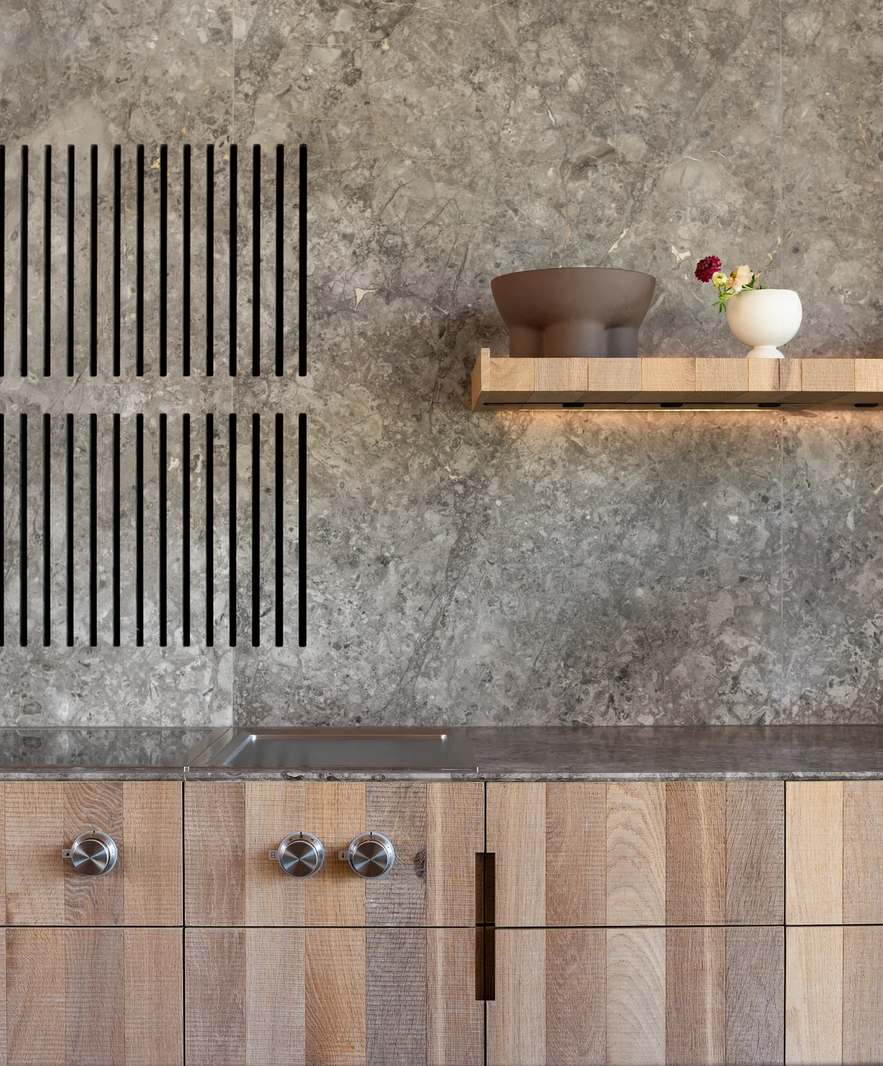 Stony Hill kitchen with gray stone backsplash, natural wood cabinets, and a floating wooden shelf holding decorative items.