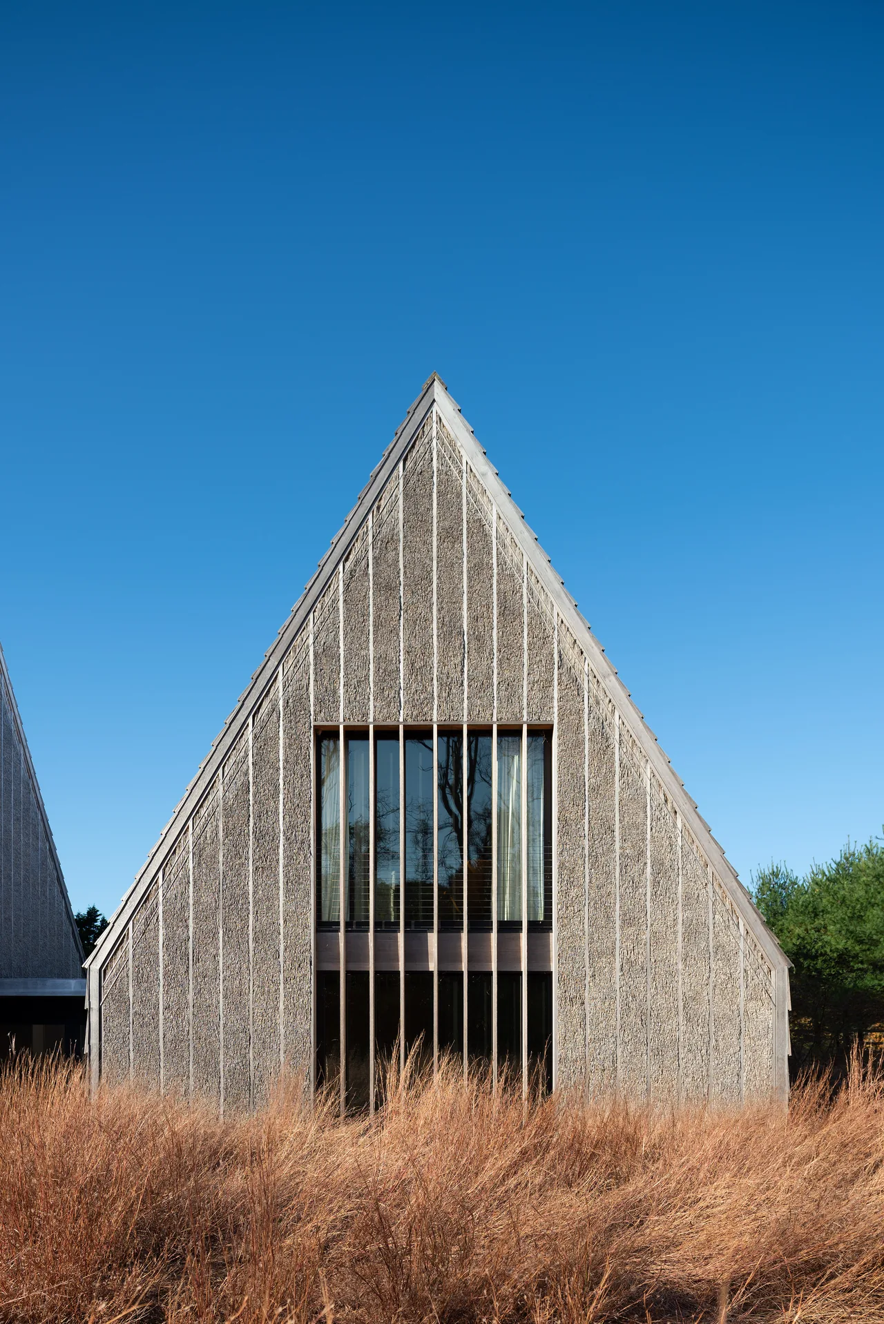 Gable end of Stony Hill residence featuring textured wood siding and a vertical band of windows.