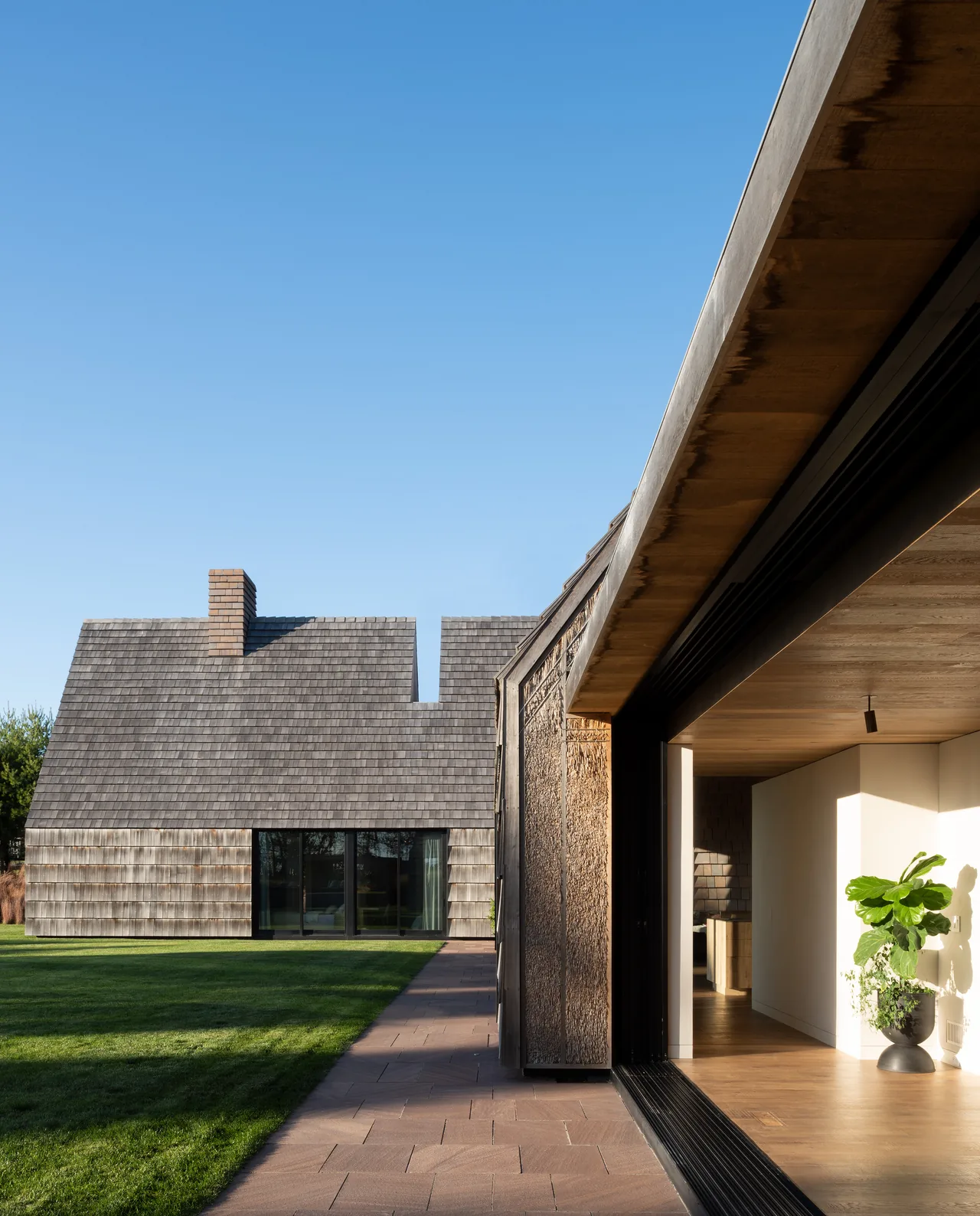 The Stony Hill project features a steep gable roof and textured shingle siding with a chimney and large glass doors.