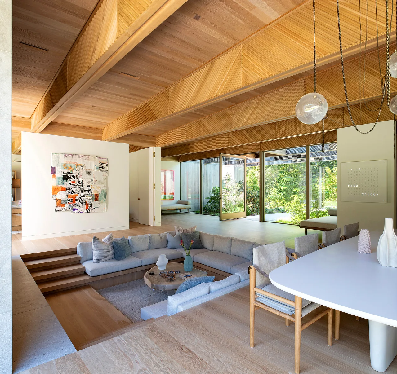 Sunken living room and dining area under a wood-paneled ceiling with integrated geometric details.