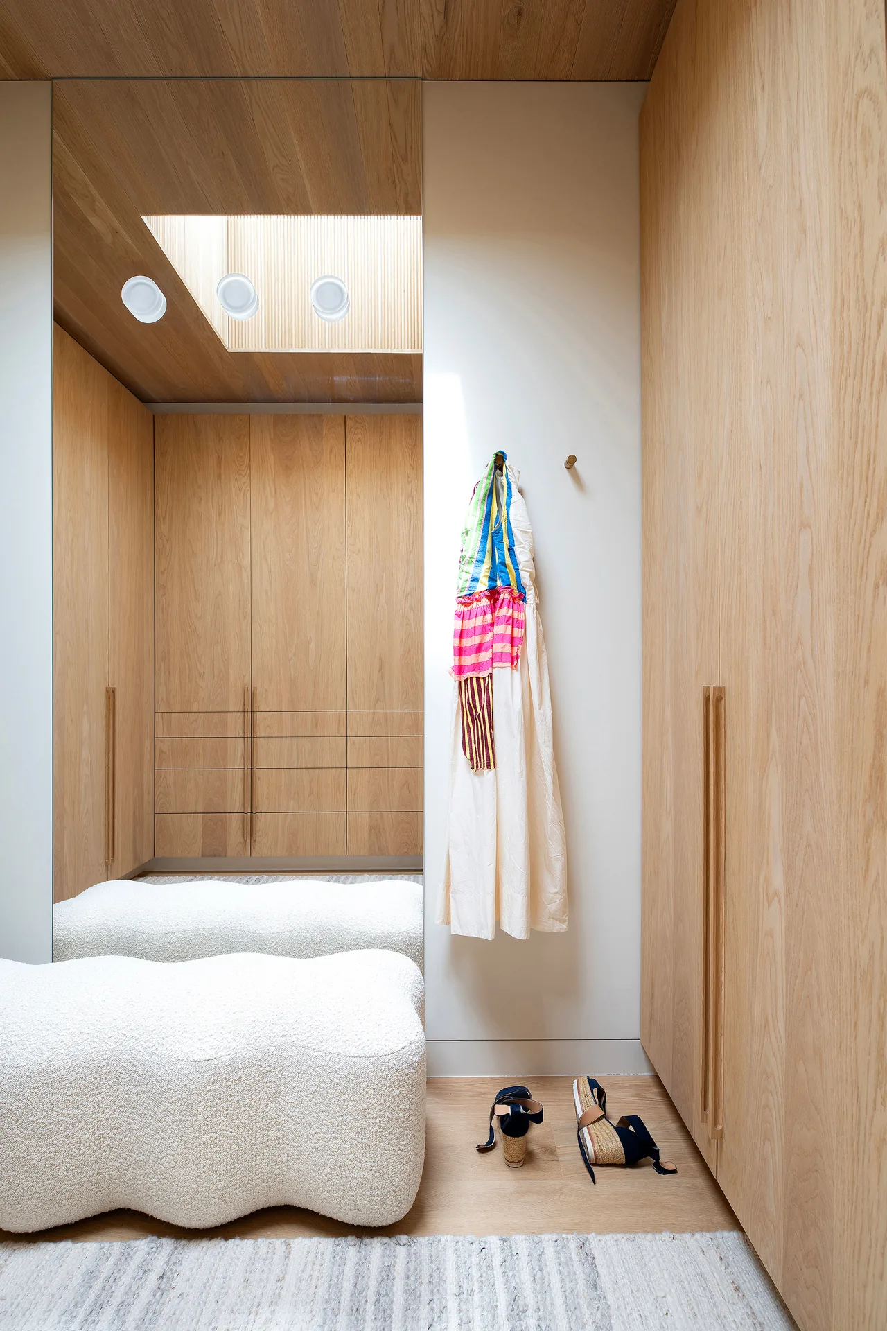 Dressing room featuring wood-paneled cabinetry and a skylight providing natural light.