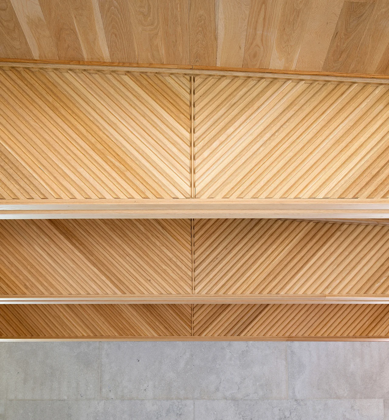 Detail of wooden cabinetry featuring diagonal slats in a chevron pattern above a stone wall.