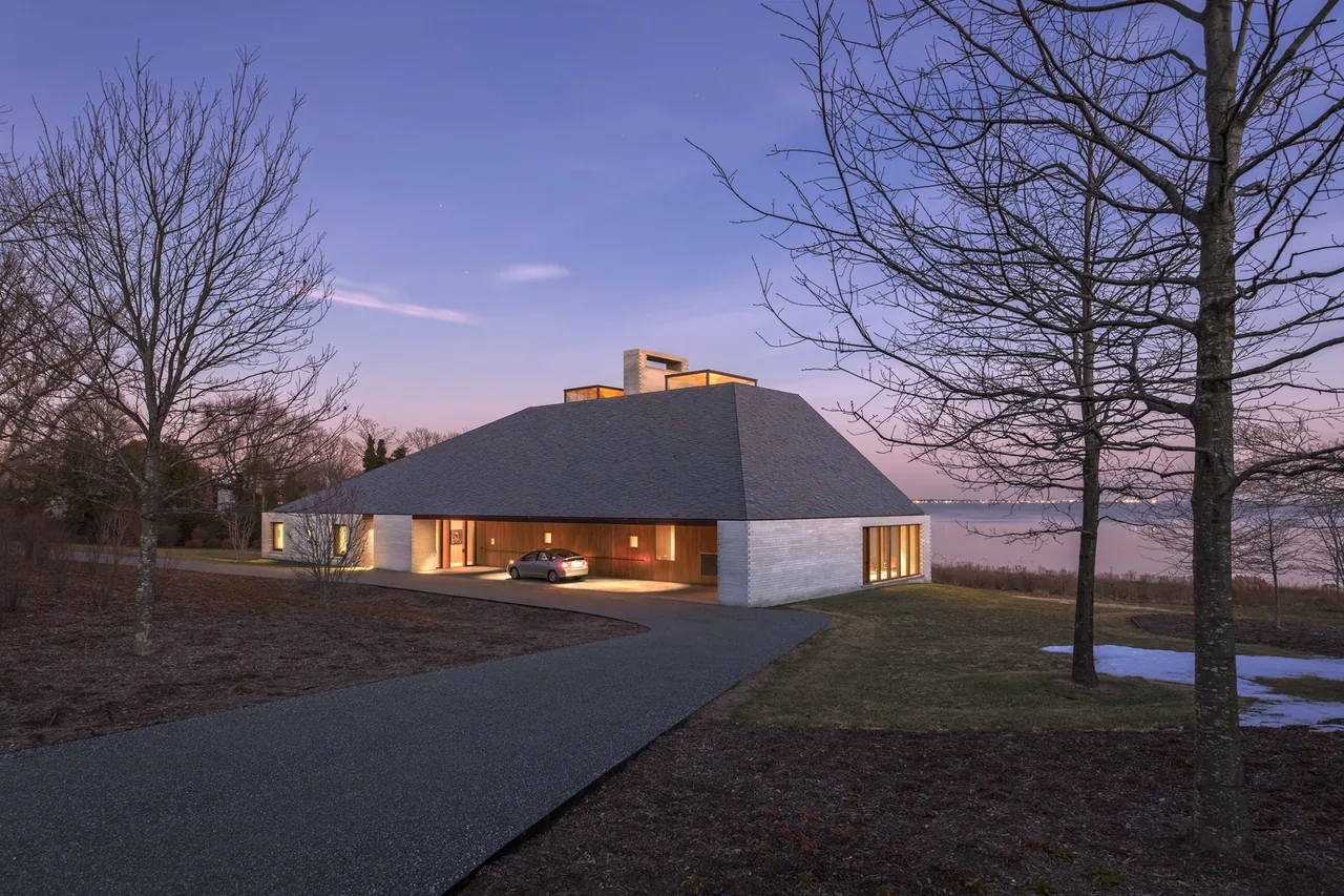 Exterior front view of the Bayhouse showing its large sloped roof and illuminated entry area at dusk.