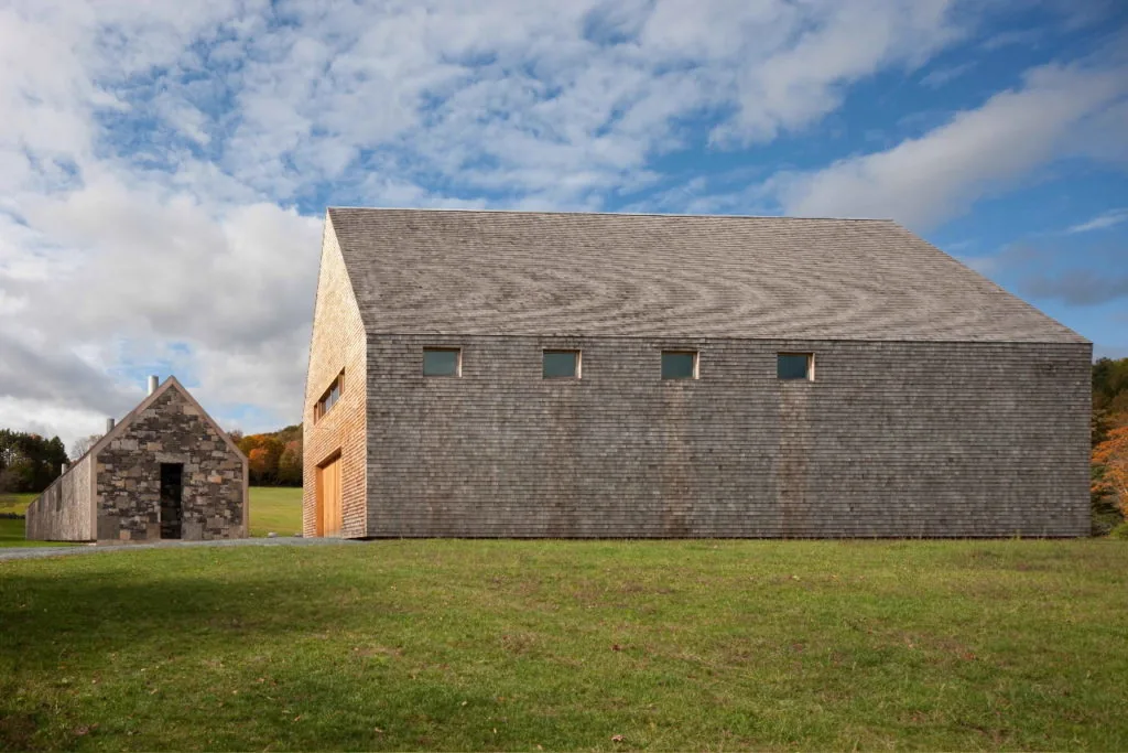 Exterior front view of two gable-roofed buildings clad in wood and stone at Woodstock Vermont Farm.