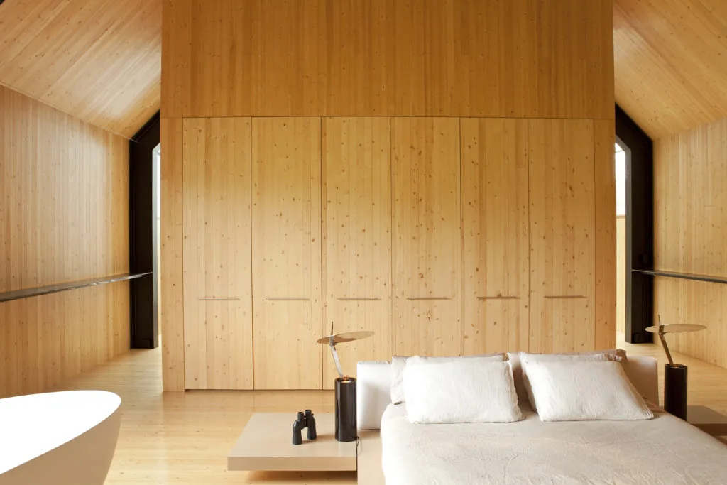 Minimalist bedroom with all-wood interior and simple furnishings in the Woodstock Vermont Farm project.
