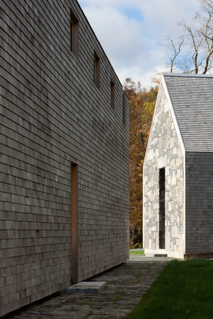 Two adjacent buildings at Woodstock Vermont Farm have contrasting facades of wooden shingles and stone.