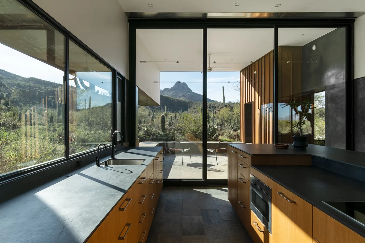 Kitchen interior with large sliding glass doors opening to an outdoor patio and desert mountain view.