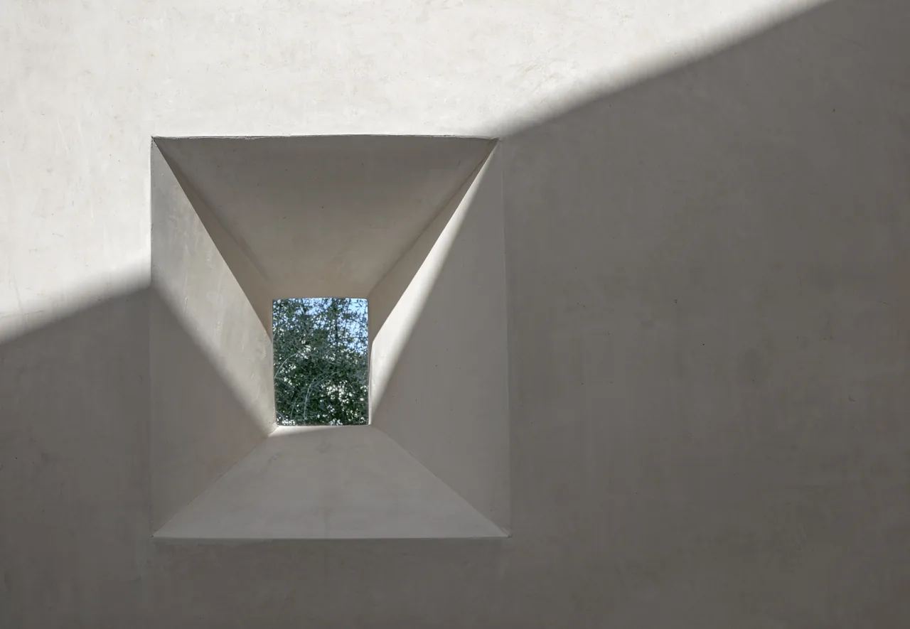 Square recessed skylight in white stucco ceiling casts angular shadows.