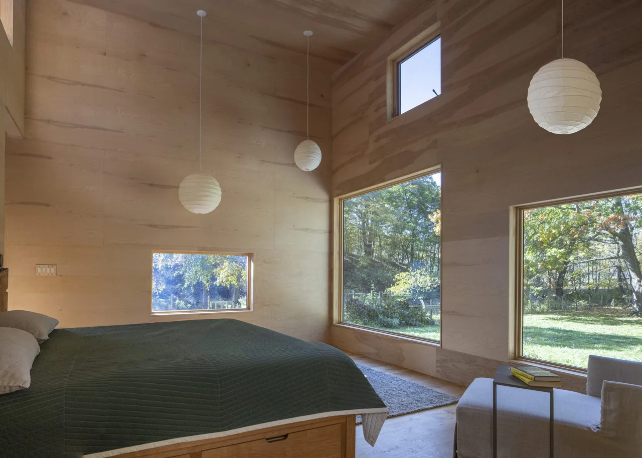 Bedroom features wood paneling and abundant natural light from multiple rectangular windows.