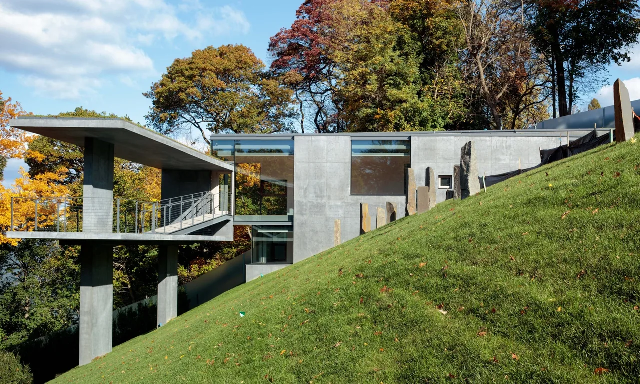 Horizon House by Steven Holl Architects showcases a concrete facade with large vertical windows on a sloped site in autumn.