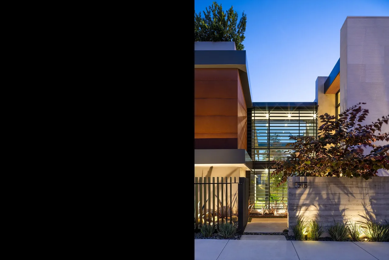 The GOLDENROD HOUSE features a modern exterior with glass walls, concrete, and warm wood siding under clear dusk sky.