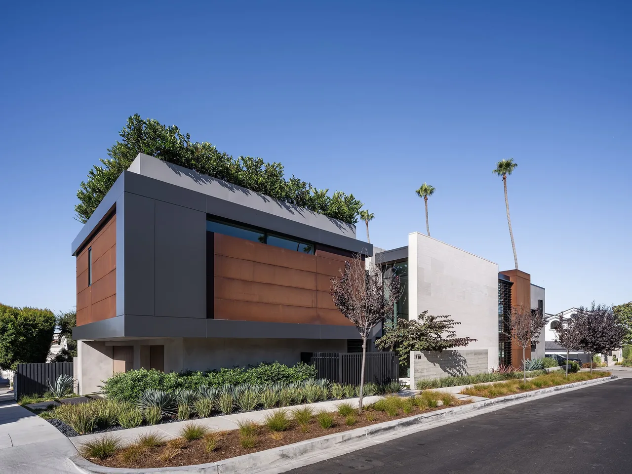 Goldenrod House features rectangular volumes with rust-colored metal panels and a planted rooftop in Los Angeles.