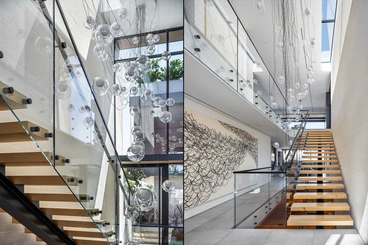 Modern stairwell in GOLDENROD HOUSE features floating wood steps, glass railings, and a distinctive bubble chandelier.