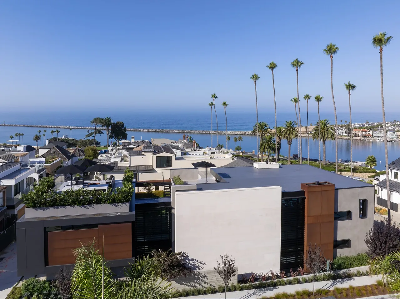 GOLDENROD HOUSE features rectangular volumes, flat roof, rust-colored metal panels, and a planted rooftop with coastal and bay view.