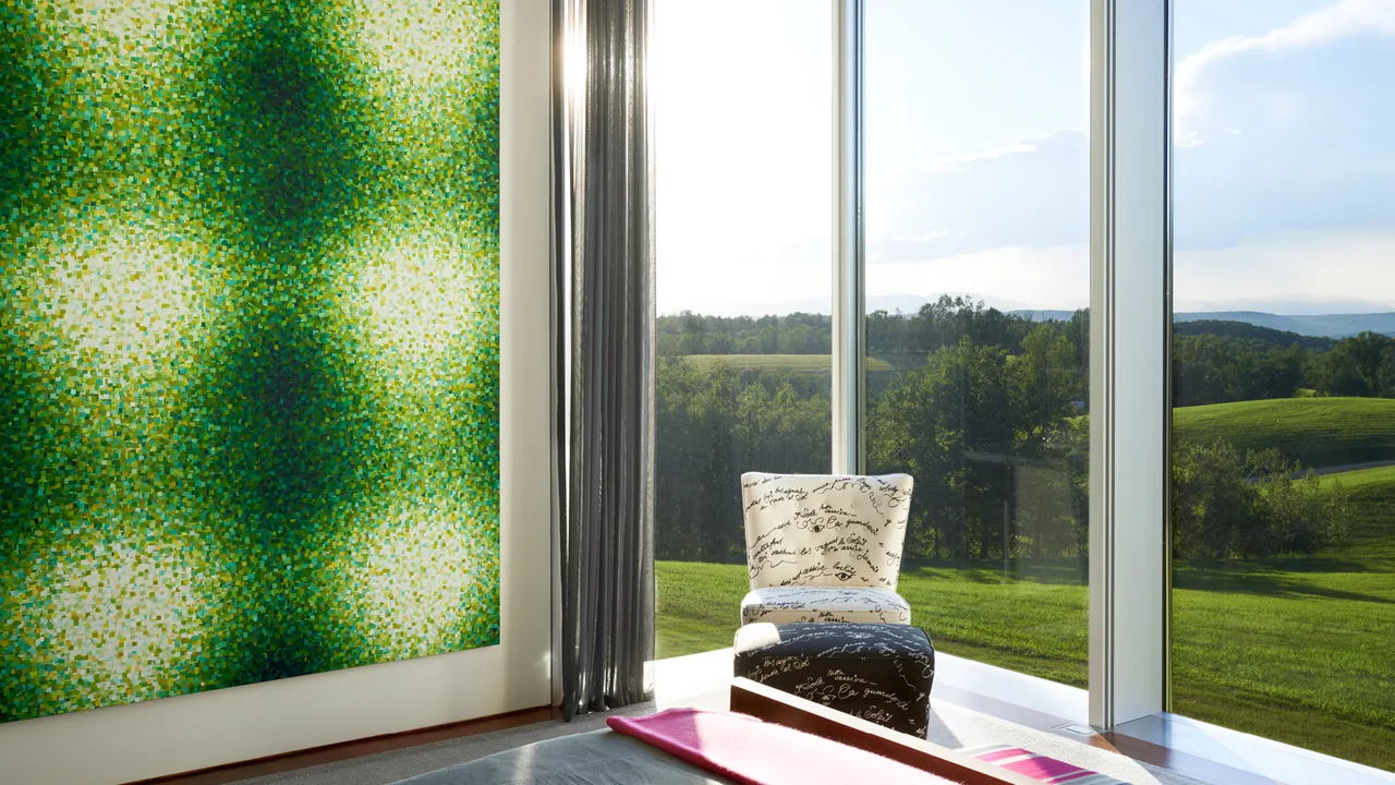 Interior seating area with large script-fabric chair and green patterned mural by floor-to-ceiling windows at Dutchess County Residence.
