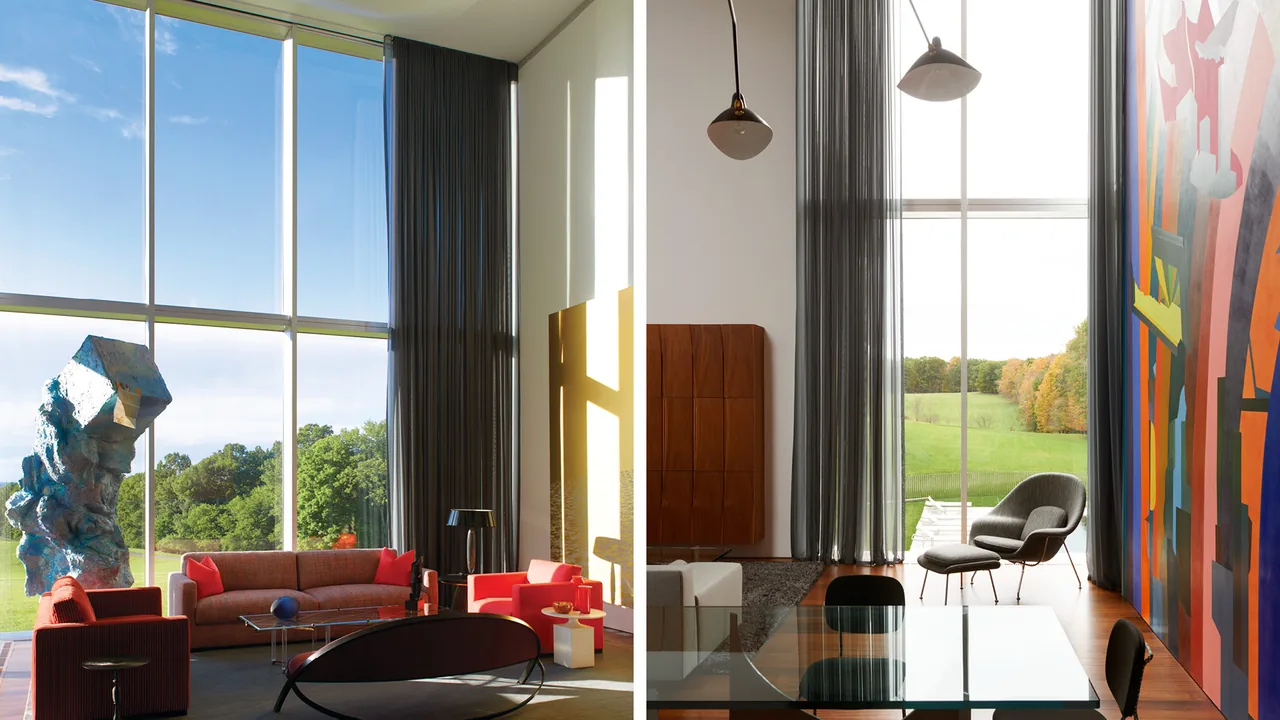 Living and dining area in Dutchess County Residence featuring floor-to-ceiling glazing with views of autumn trees and a large grassy field.
