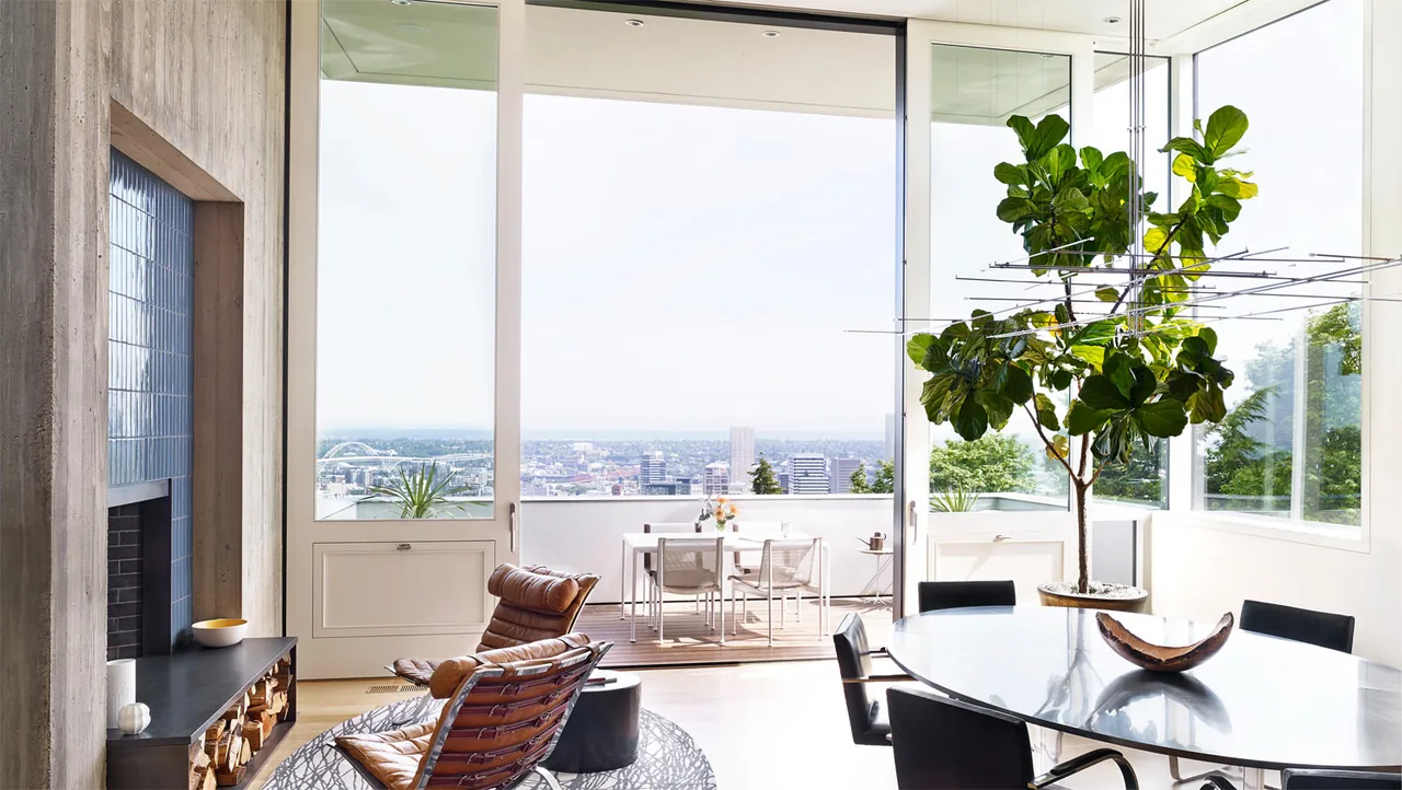 Living and dining area with full-height glass doors opening to a balcony and city views in the Portland Heights Residence.