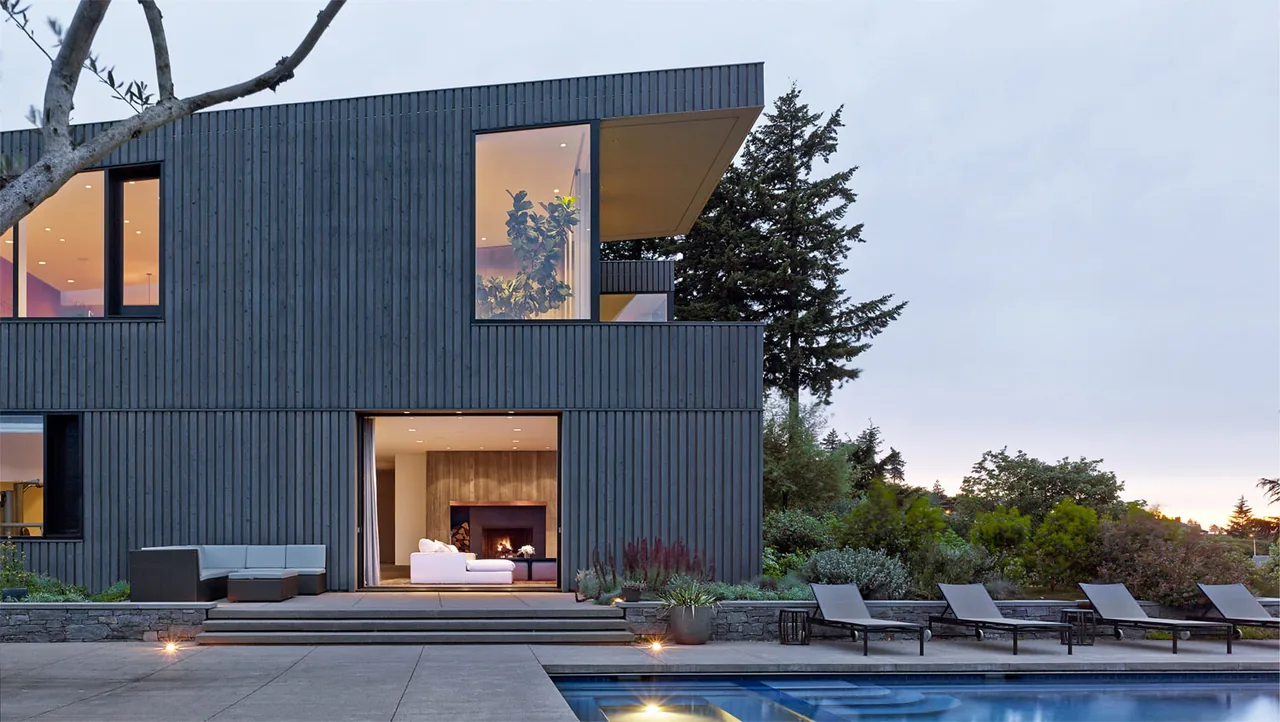 Portland Heights Residence features dark vertical wood siding, large corner windows, and an outdoor pool area with lounge seating.
