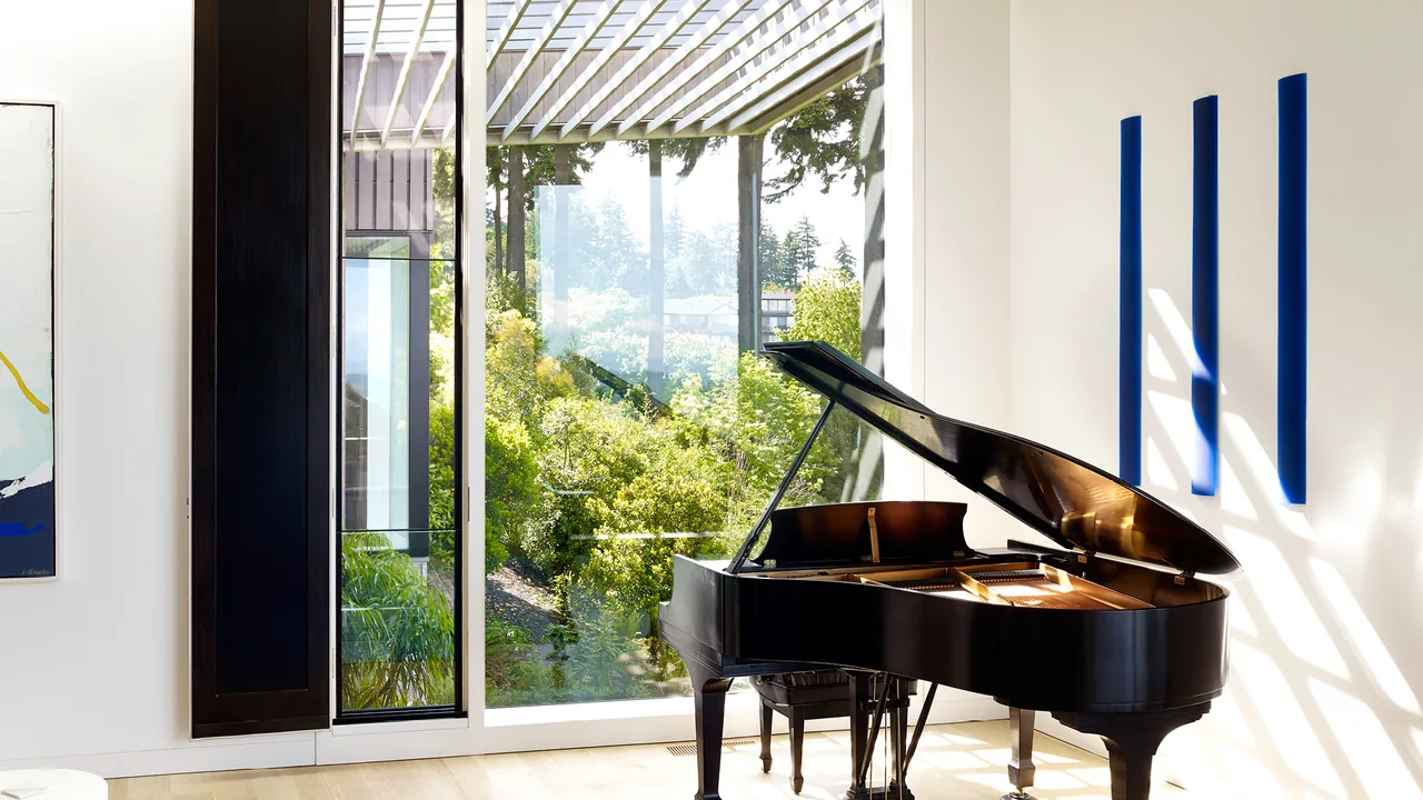 The Portland Heights Residence features a grand piano by large glass windows overlooking landscaped greenery.