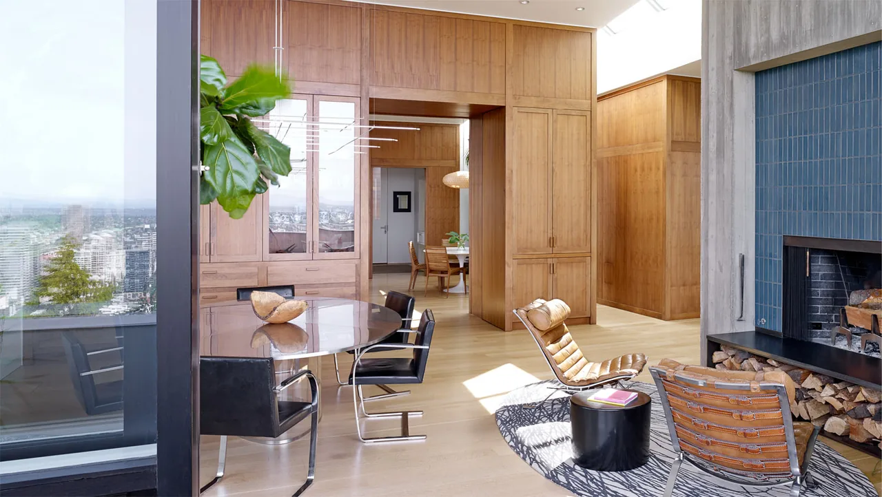Portland Heights Residence living room features wood paneling, a blue tiled fireplace, and large windows with city views.
