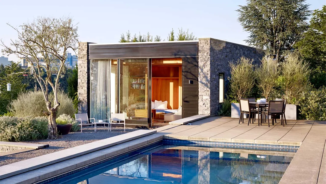 Poolside view of Portland Heights Residence showing stone and wood exterior with seating areas and mature landscaping.