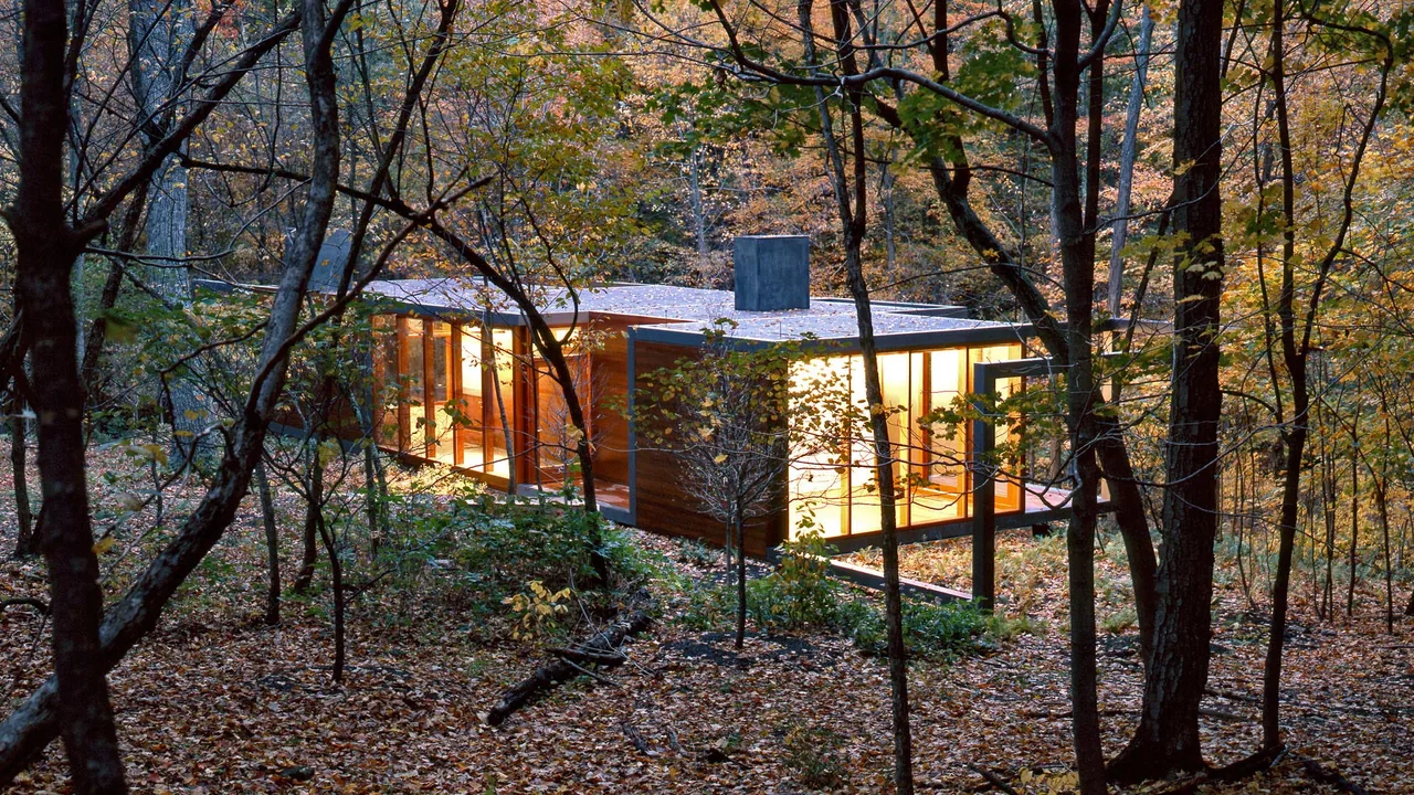The Dutchess County Residence Guest House shows modern design with floor-to-ceiling glazing and wood siding in a forest setting.