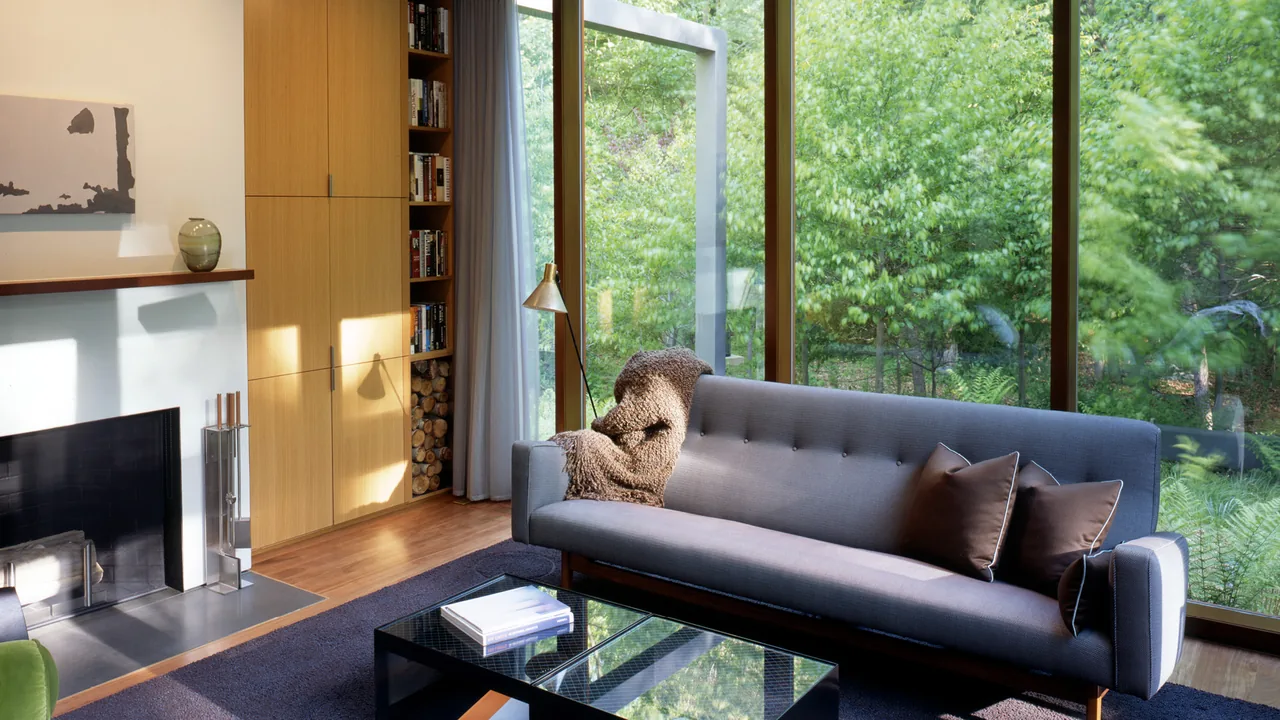 Living room of Dutchess County Residence Guest House featuring floor-to-ceiling glazing and built-in wood shelving.