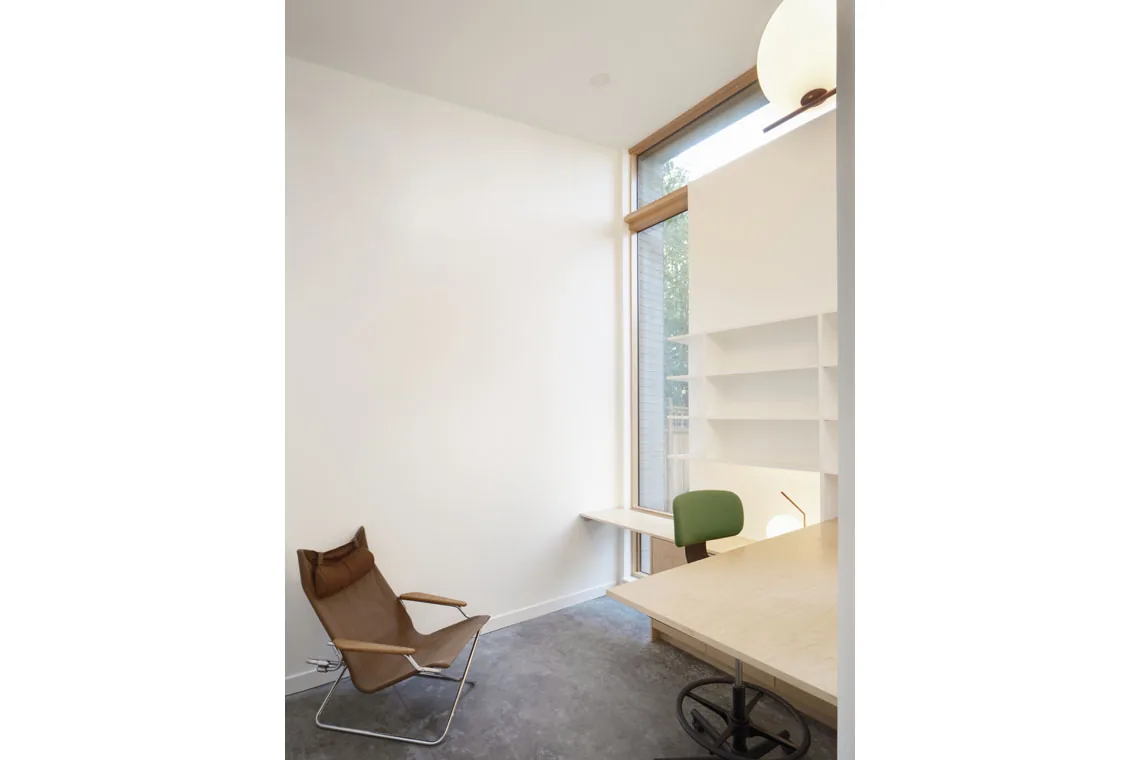 Small office corner featuring a tall window, built-in shelving, and a simple desk setup.