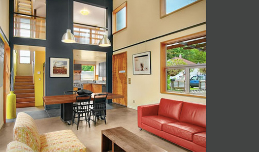 Living and dining area in Donovan Street House features a red leather sofa, wooden dining table, and abundant natural light from large windows.