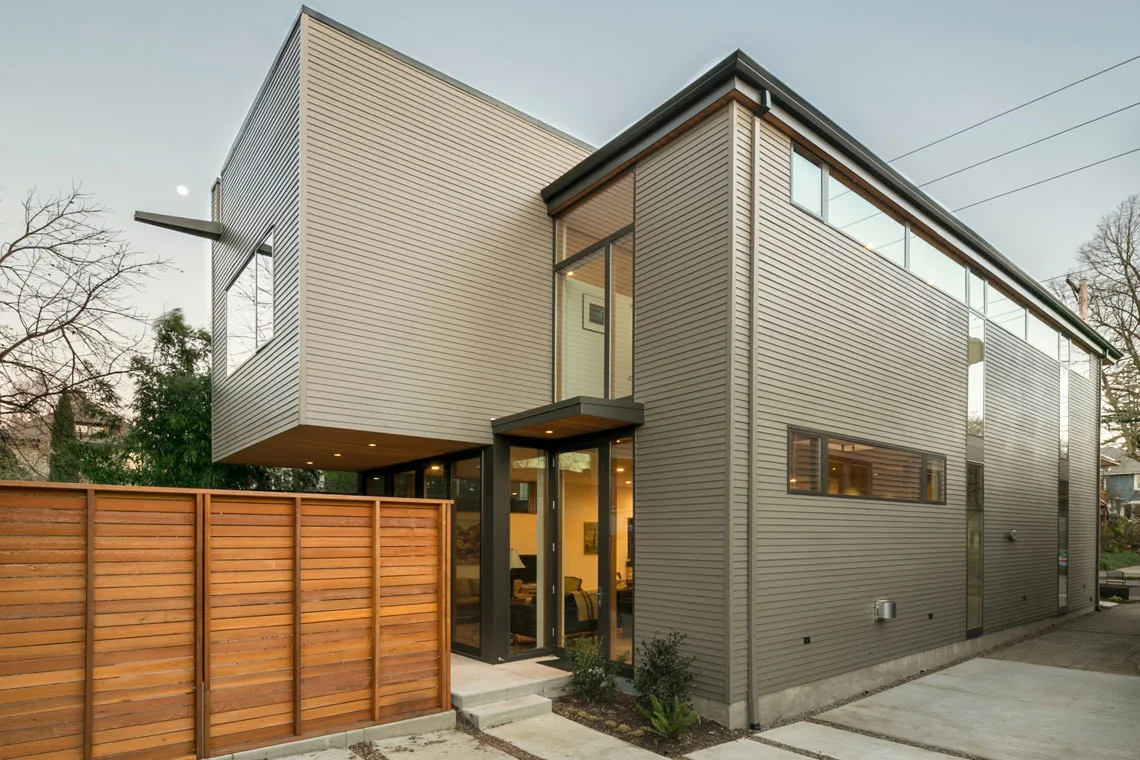 Residence: Portland features a cantilevered upper floor with horizontal siding and large glass entryway.