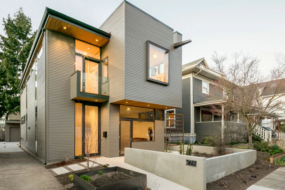 Residence Portland features horizontal siding, cantilevered second story, large glass entry, and a decorative metal screen at the entrance.