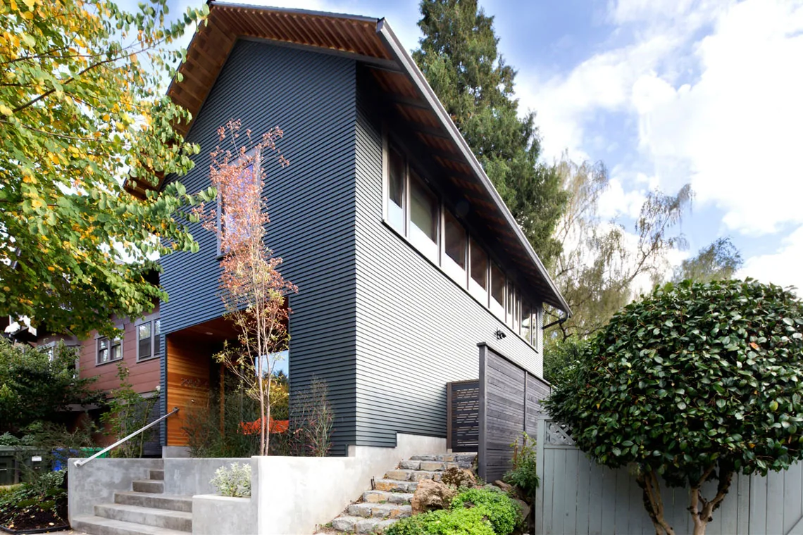 Portland ADU by Webster Wilson Architect features horizontal siding and a gable roof with visible orange chairs through the entry window.