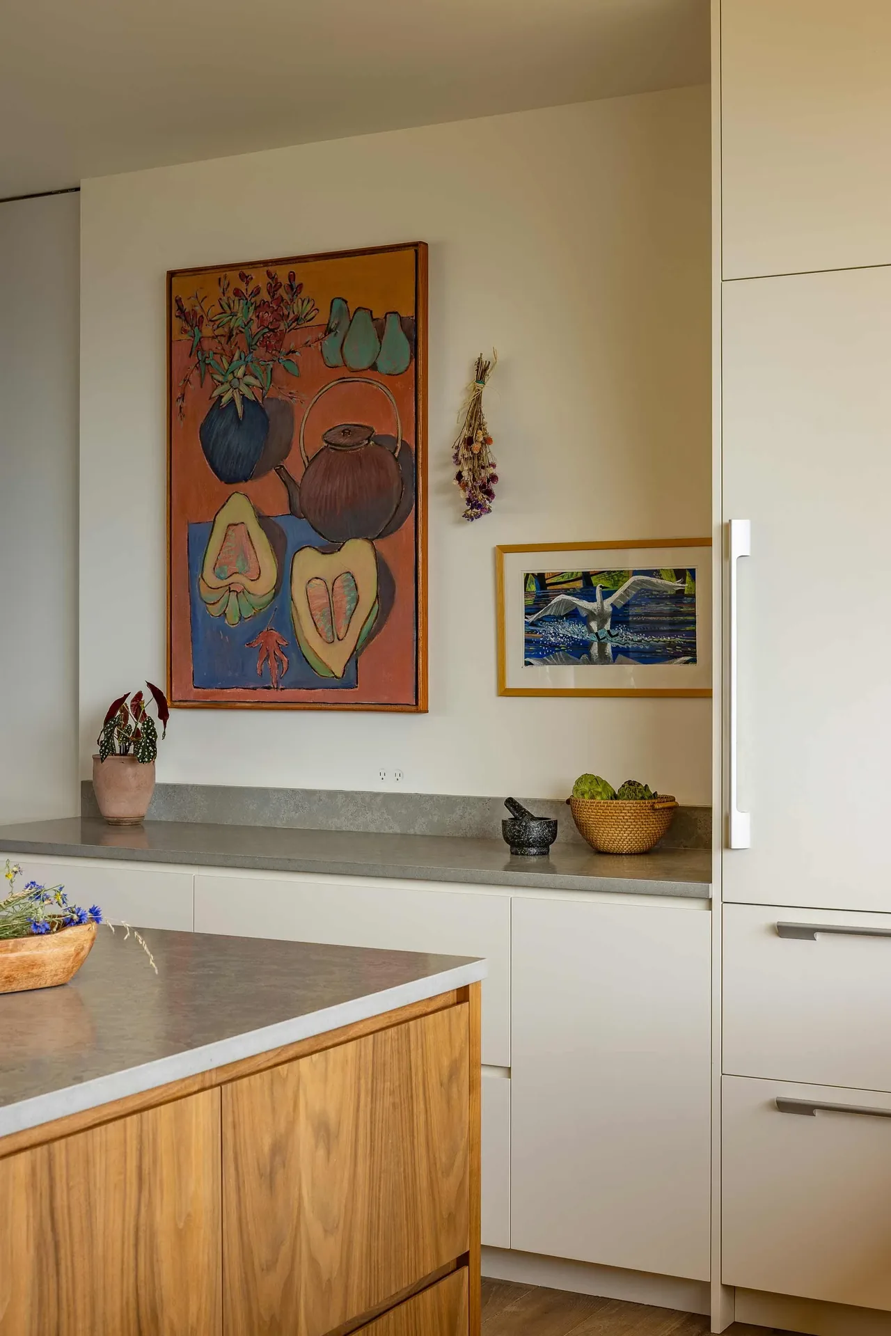 Kitchen corner featuring white cabinetry, a wooden island, and colorful artwork on the wall.