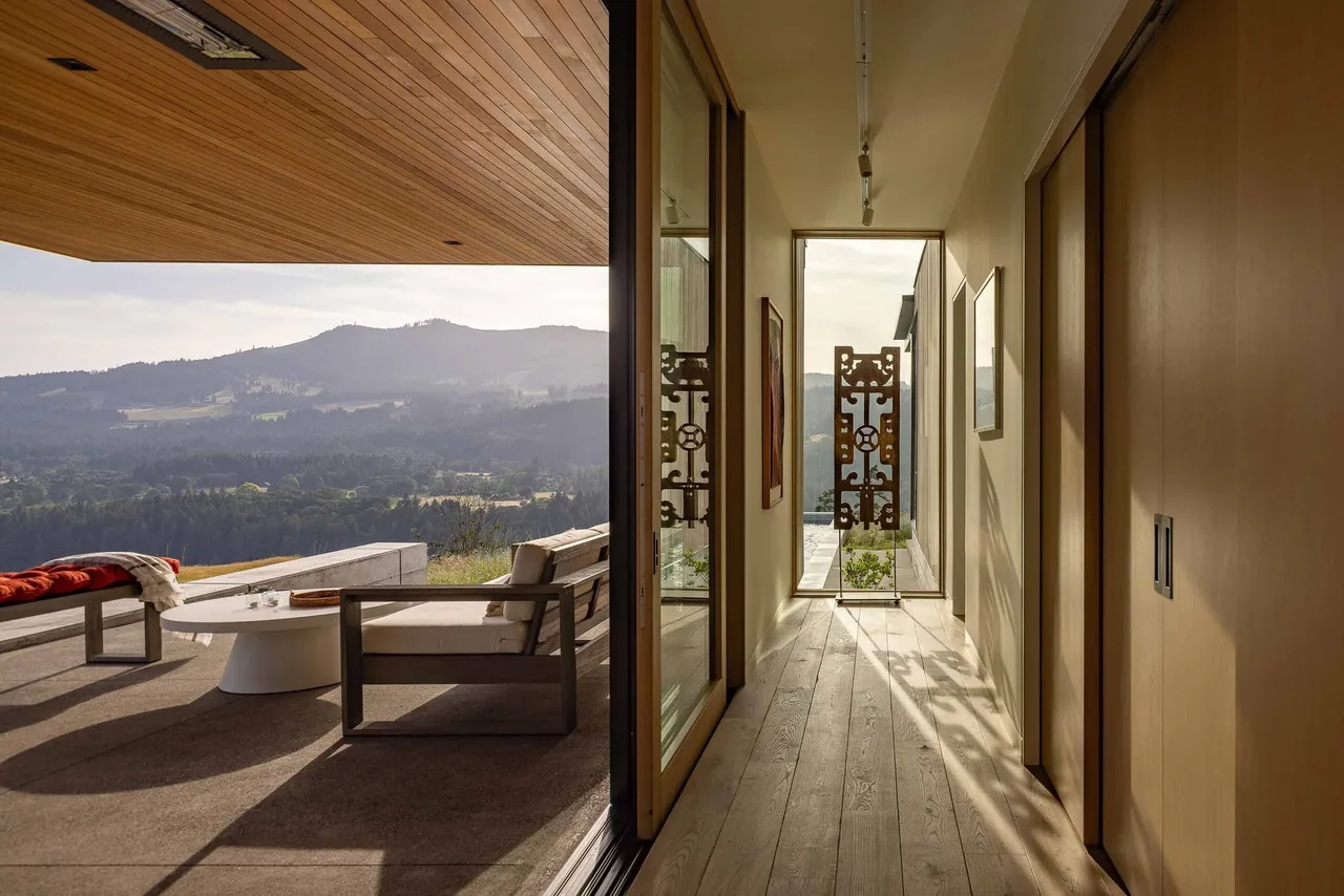 Looking from a hallway out to an outdoor patio with seating and mountain views at Bald Mountain Residence.