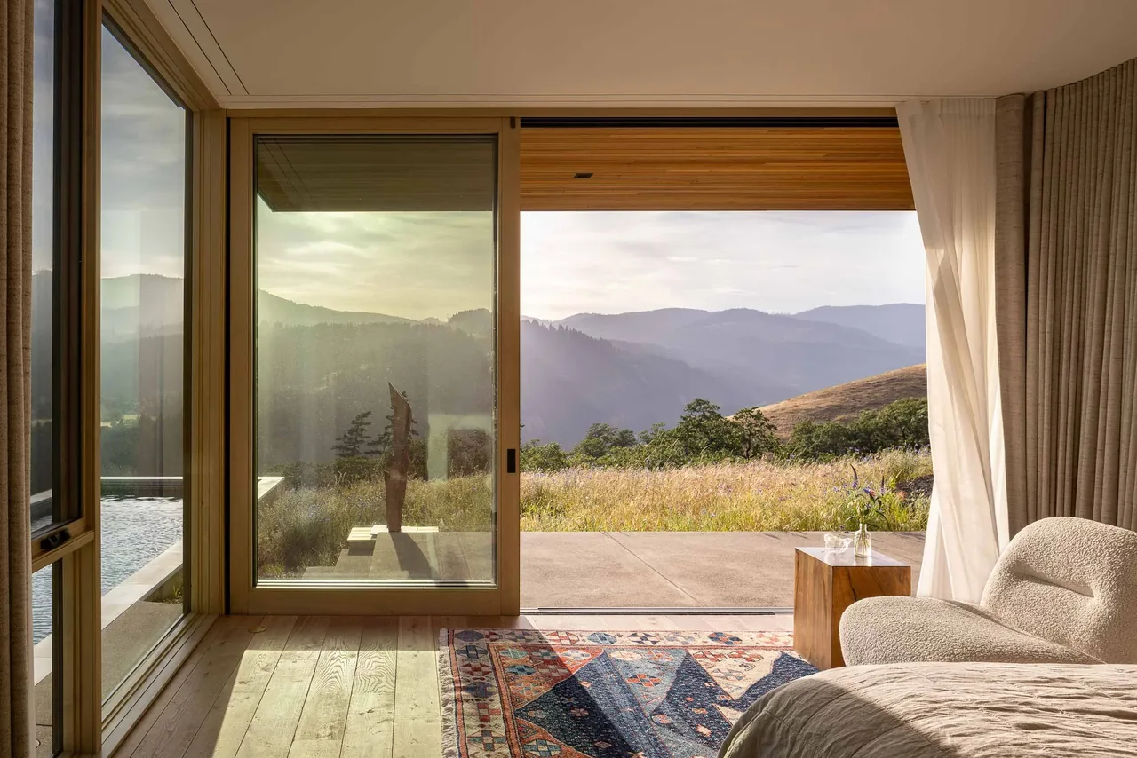 The Bald Mountain Residence bedroom features large sliding glass doors that open to a patio with expansive mountain views.