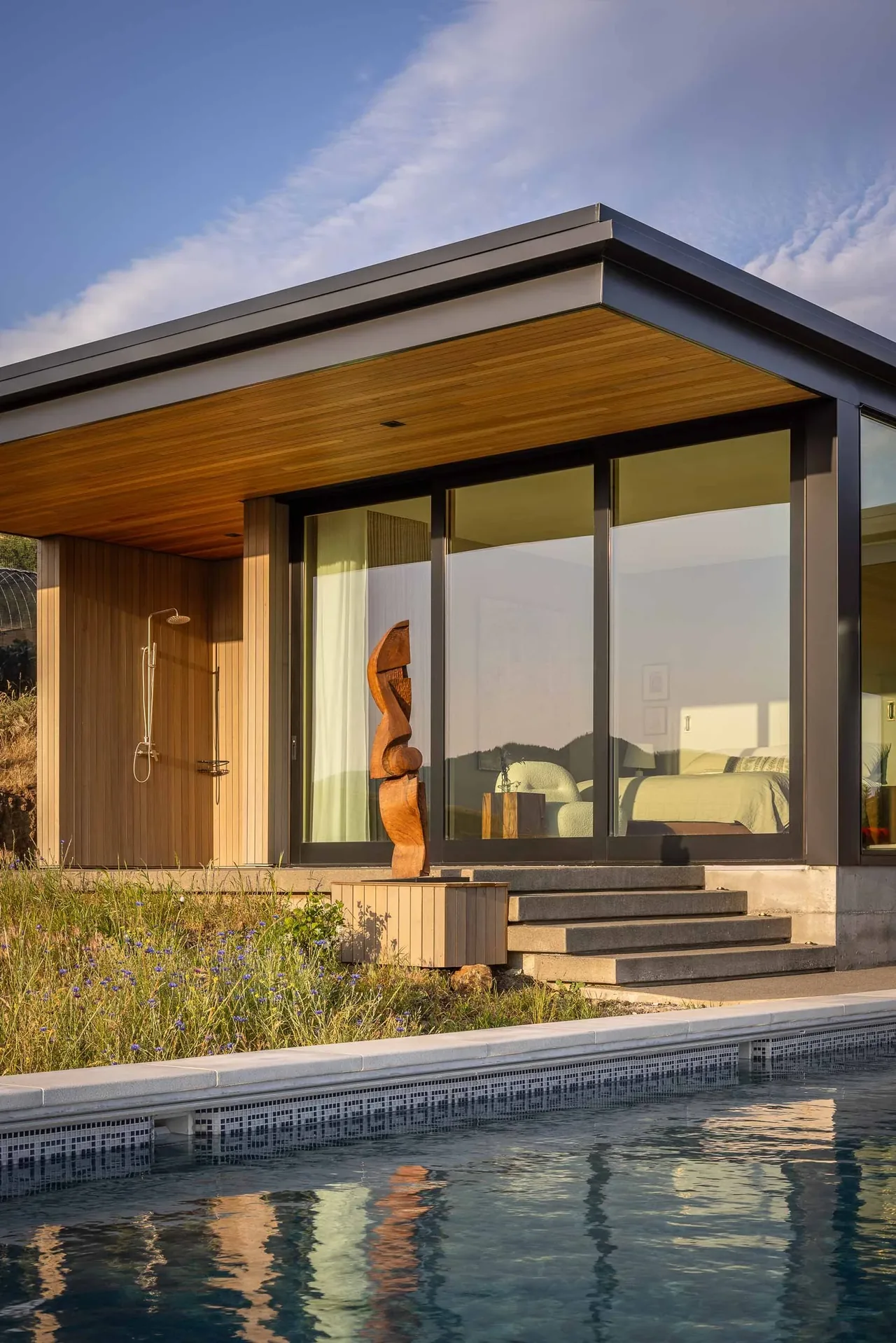 Wood-clad exterior with cantilevered roof overhang, sliding glass doors, and outdoor shower at Bald Mountain Residence.