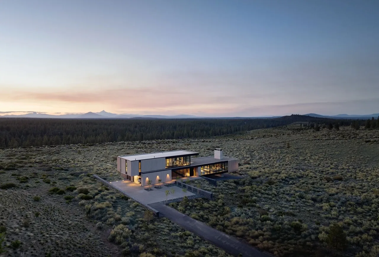 The Expanse is a modern two-story house with large glass windows and a flat roof, surrounded by open land.