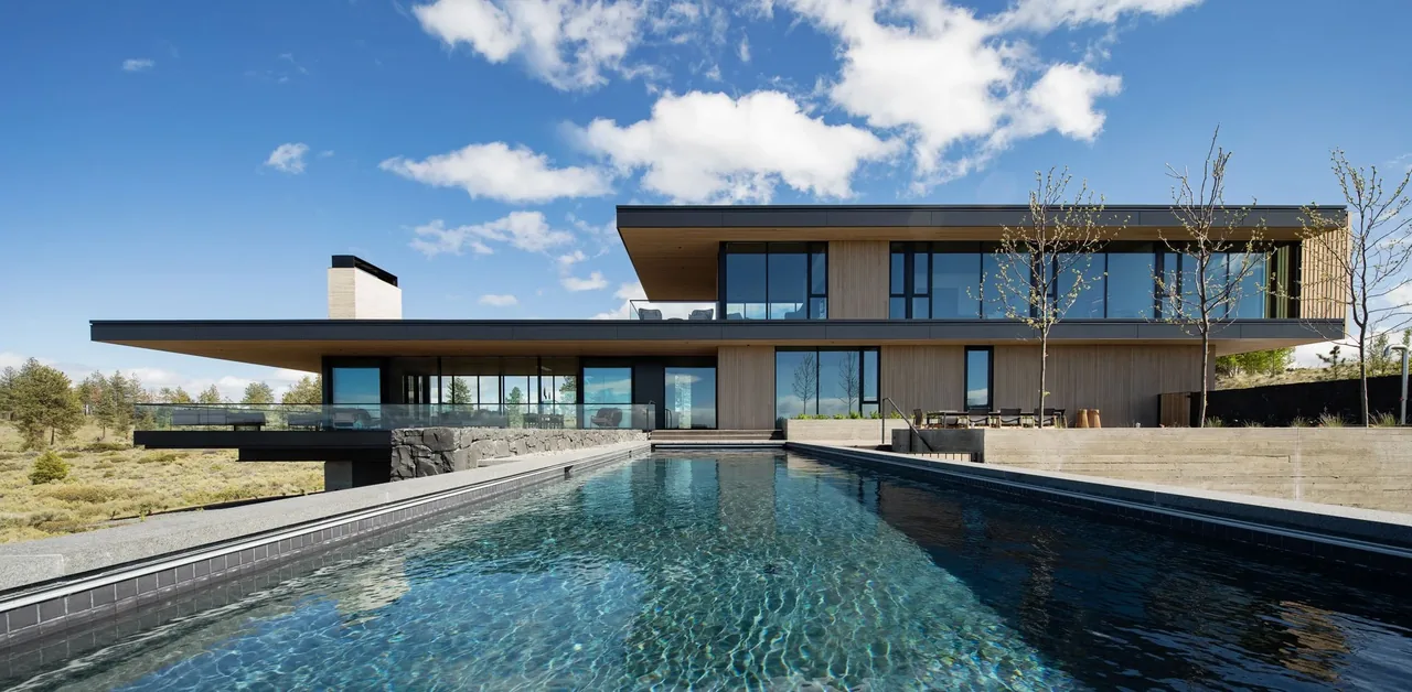 The Expanse features wood siding and expansive glazing with a pool extending from the rear.