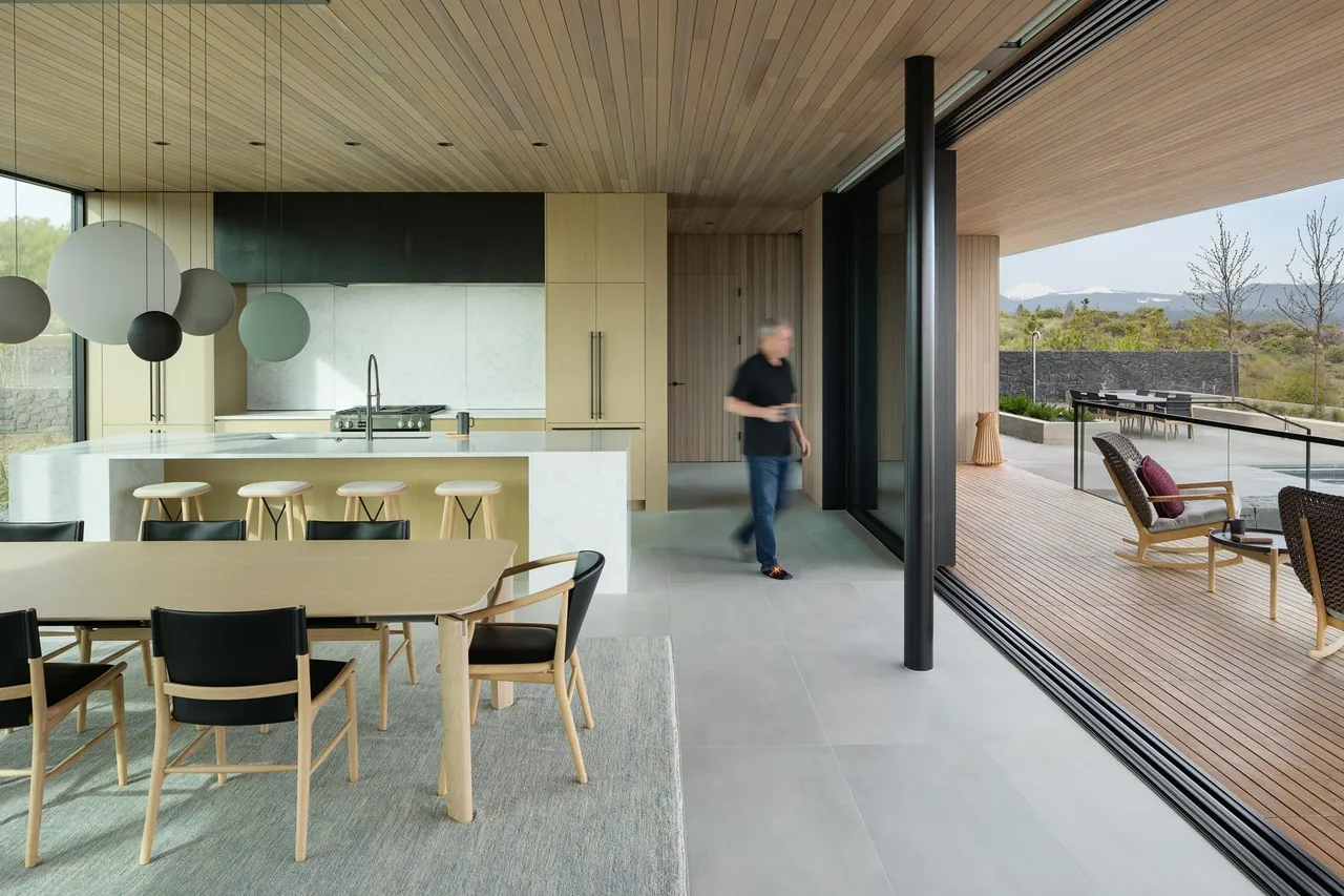 Open-concept kitchen and dining space with large island and sliding glass doors leading to a covered patio with landscape views in The Expanse project.
