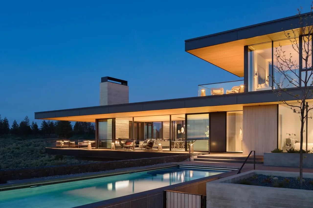 The Expanse features expansive glass walls, black window frames, and an illuminated outdoor pool area.