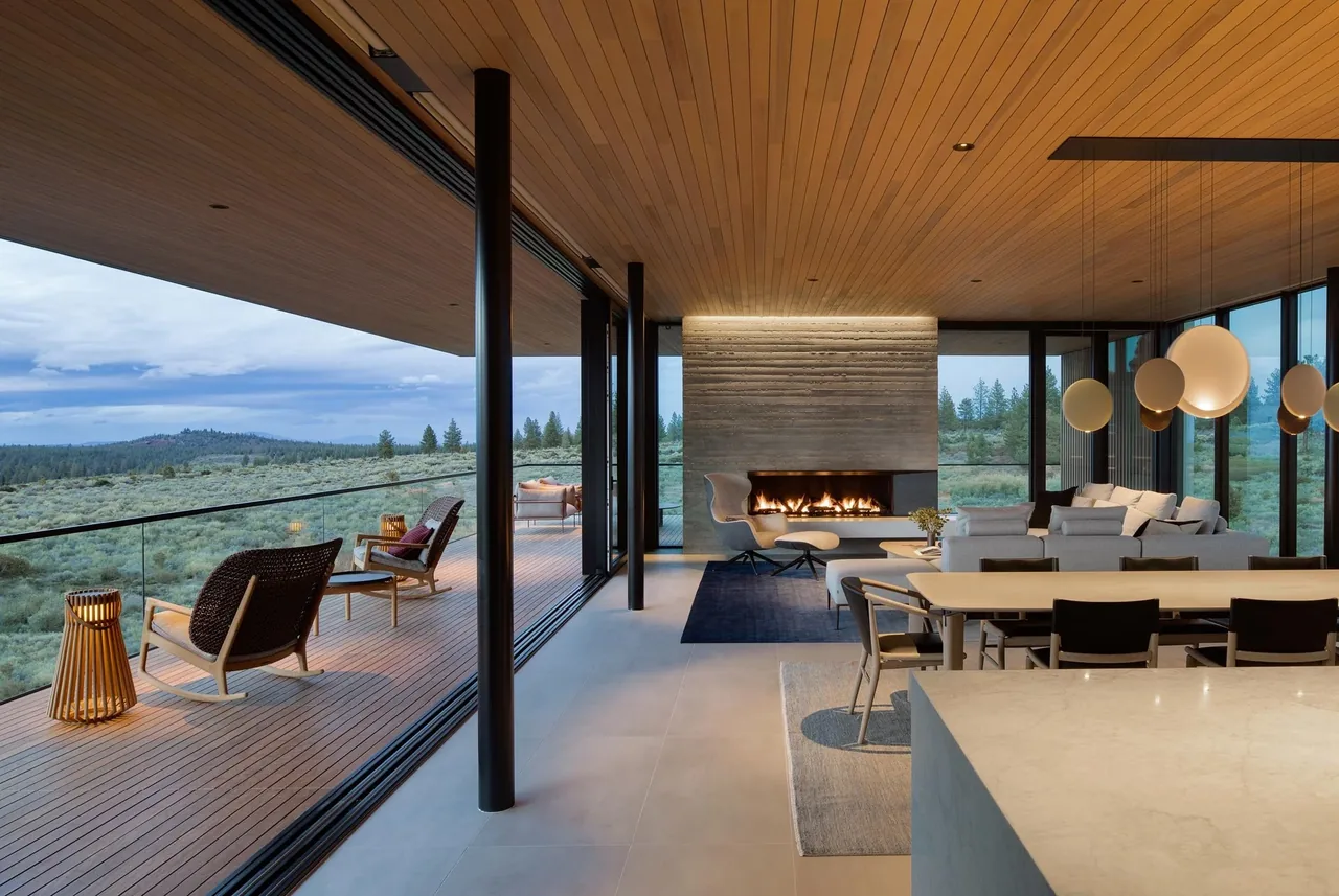 The Expanse features a modern open-plan living and dining area with floor-to-ceiling glass walls opening to an outdoor deck with landscape views.